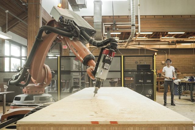 Industrial robot milling a plywood panel in a workshop