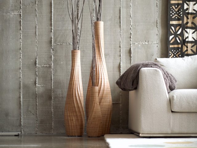Three AESTUS vases with branches against a concrete wall
